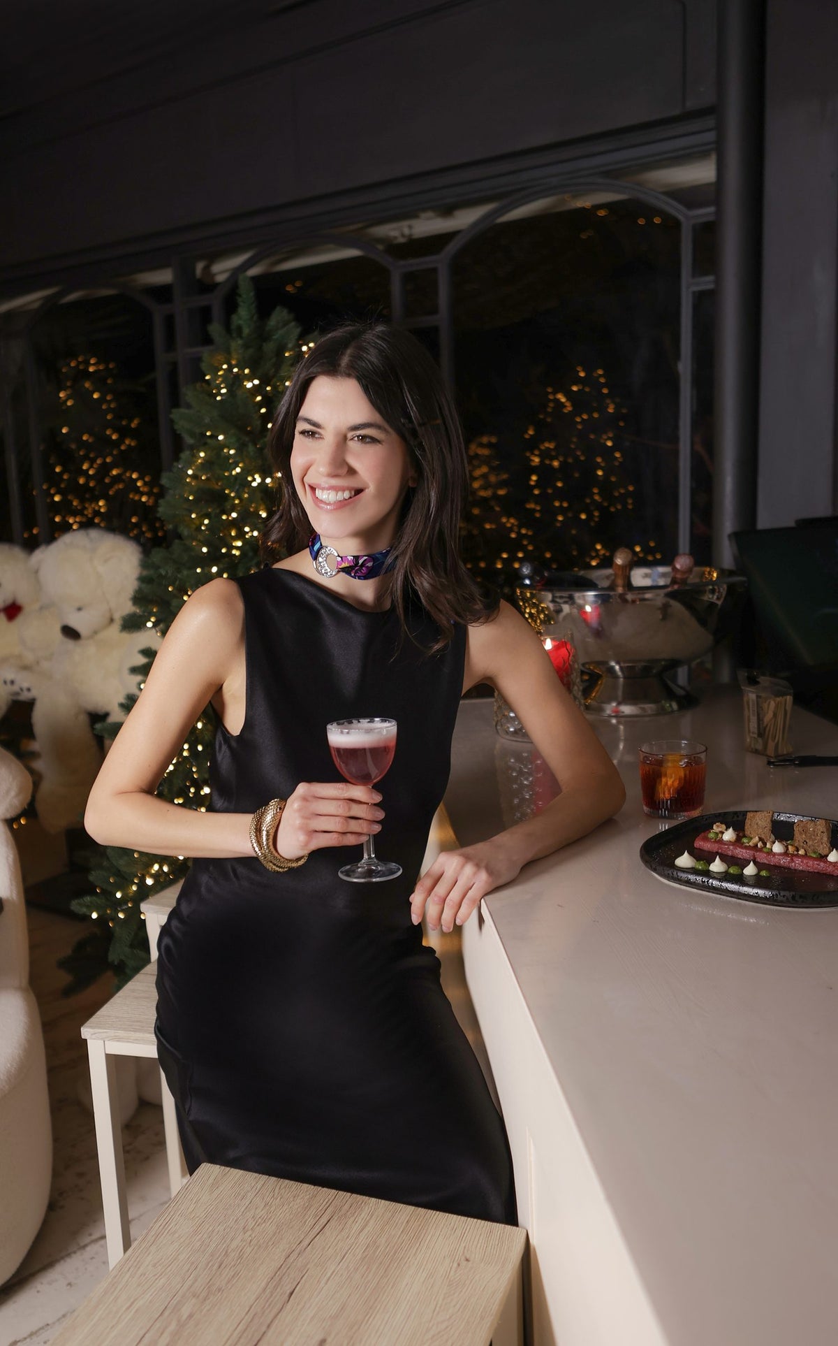 Mulher de vestido preto com um cocktail e um MeSilk MEVOY ao pescoço, durante uma festa