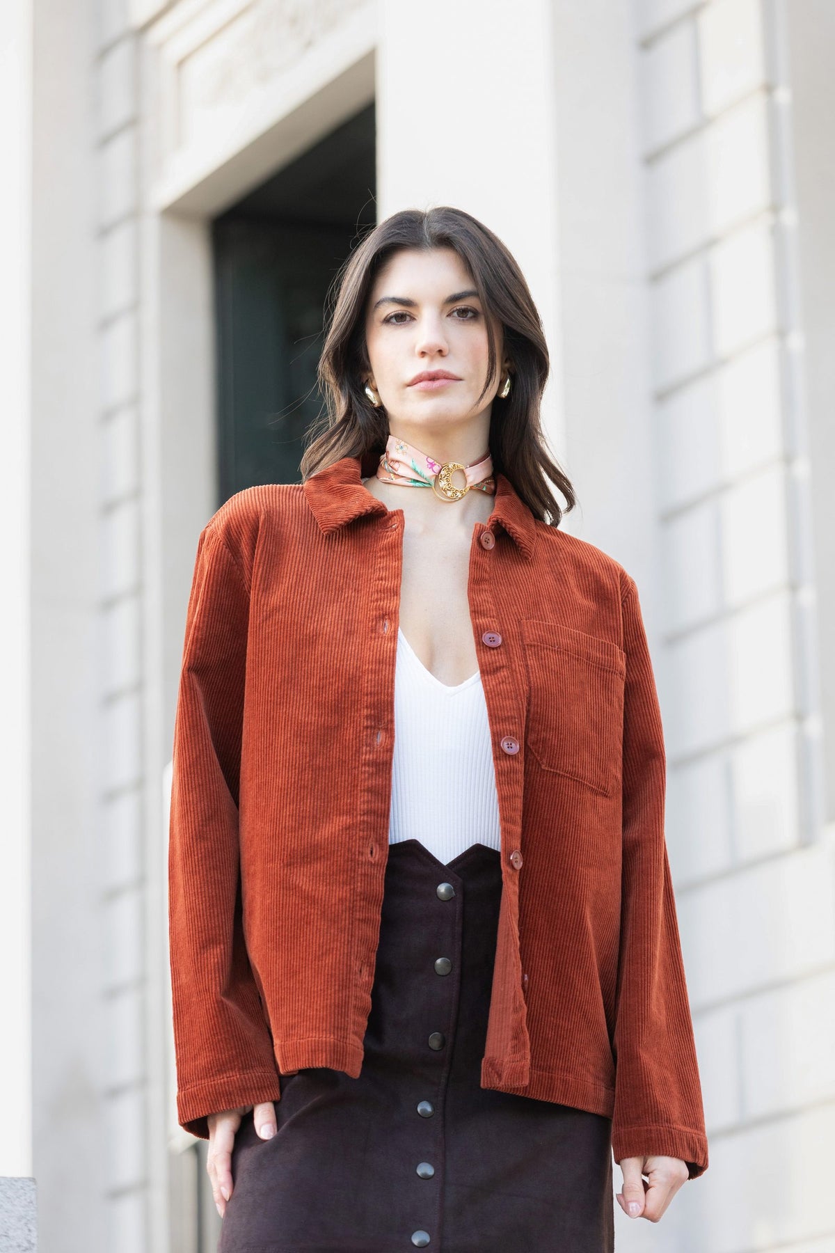 Frau in rostroter Cordjacke mit einem MEVOY MeSilk und Embrace am Hals, vor einer Villa am Comer See